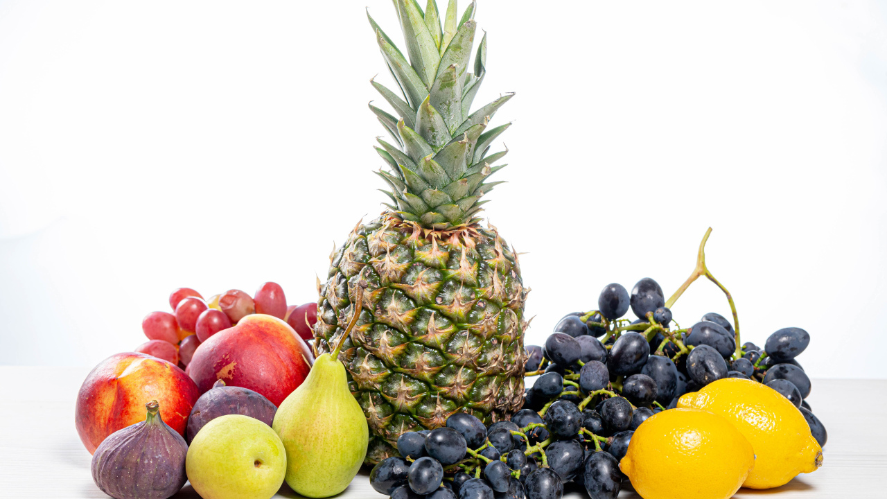 Ананас, виноград, инжир, лимон, нектарин и груши на белом фоне