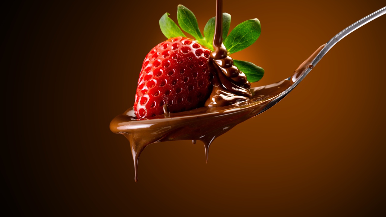 Красная клубника на ложке с молочным шоколадом