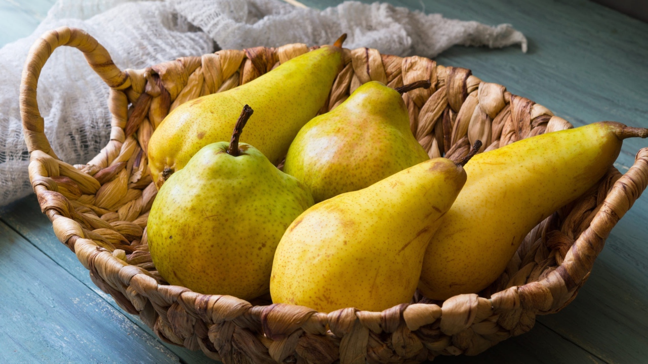 Спелые груши лежат в корзине на столе
