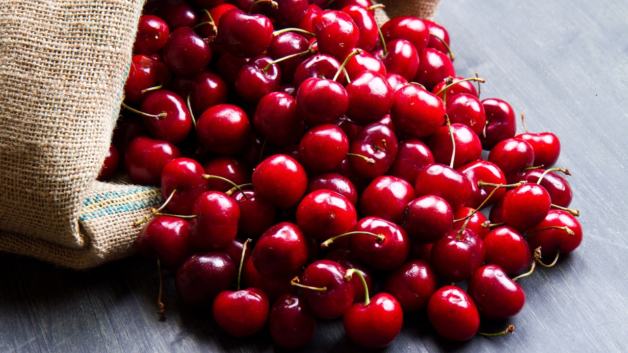 Спелые красные черешни в мешке на столе 