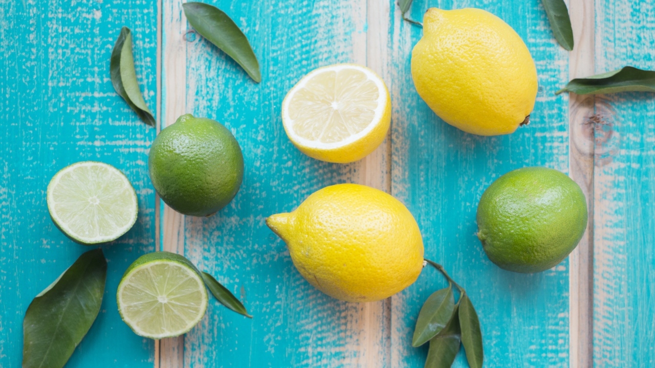 Желтые лимоны и зеленые плоды лайма на столе 