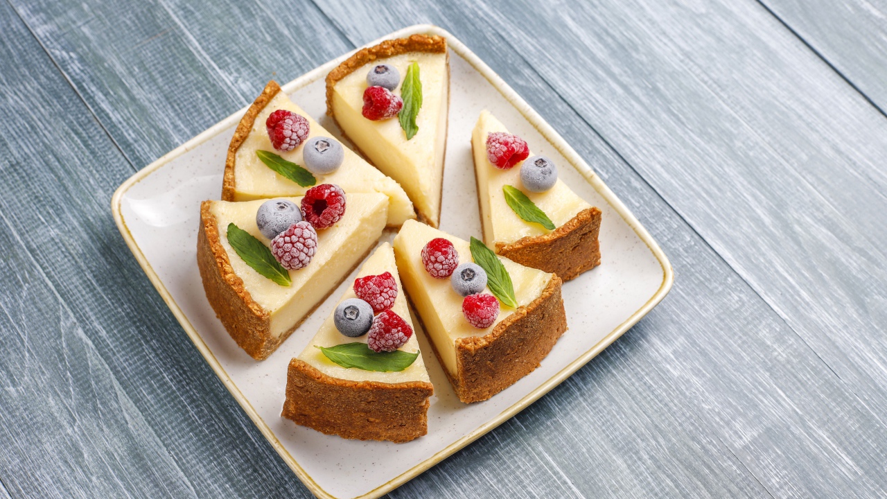 Аппетитный чизкейк с ягодами нарезан кусками на тарелке 