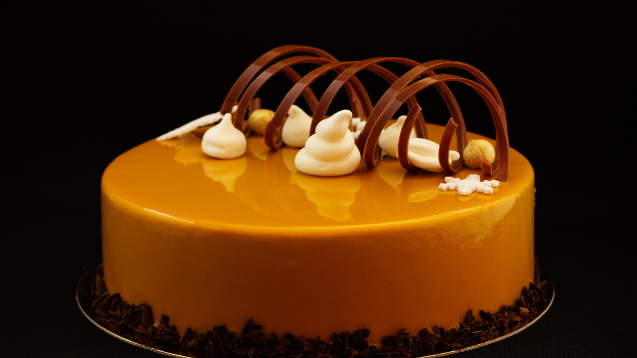 Красивый глянцевый оранжевый торт на черном фоне