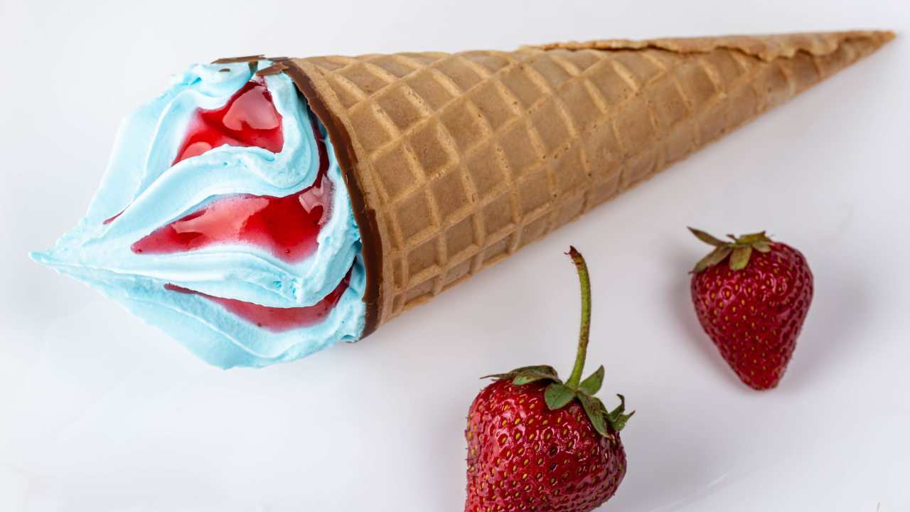 Рожок с голубым мороженым на сером фоне с клубникой 