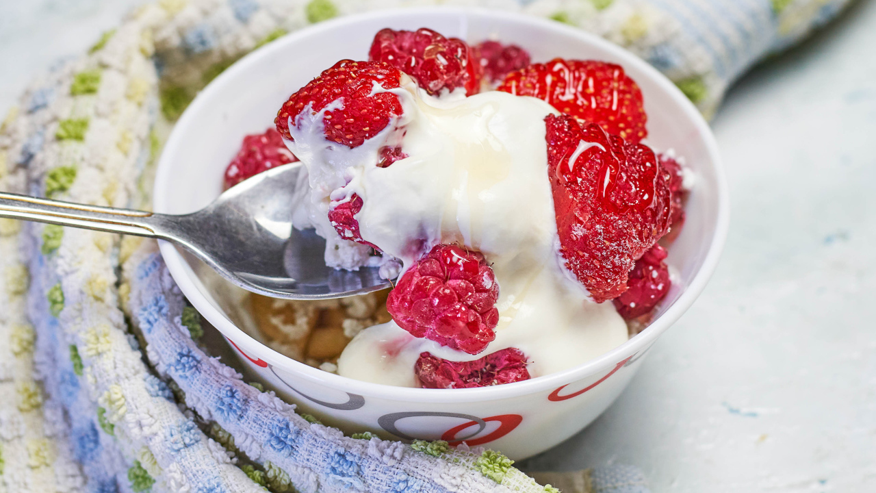 Завтрак с йогуртом и малиной в миске с ложкой