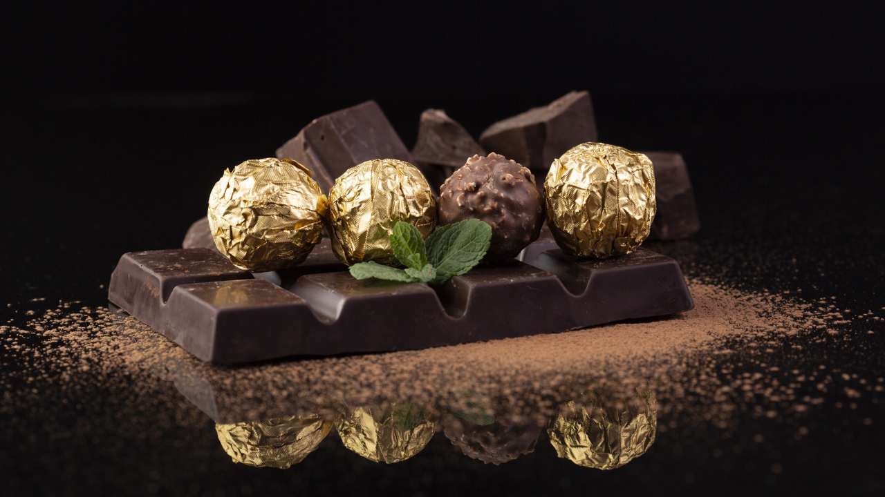 Плитки черного шоколада с конфетами на столе 