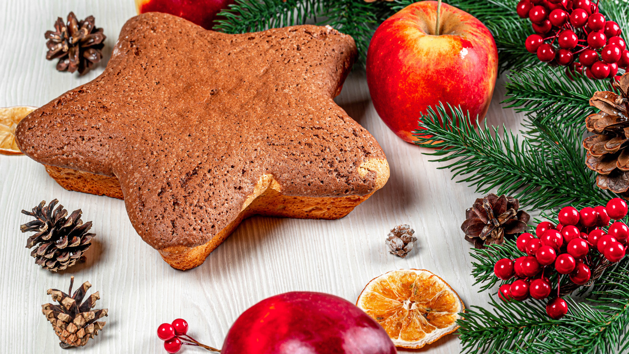 Рождественский кекс на столе с еловыми ветками,  яблоками и шишками