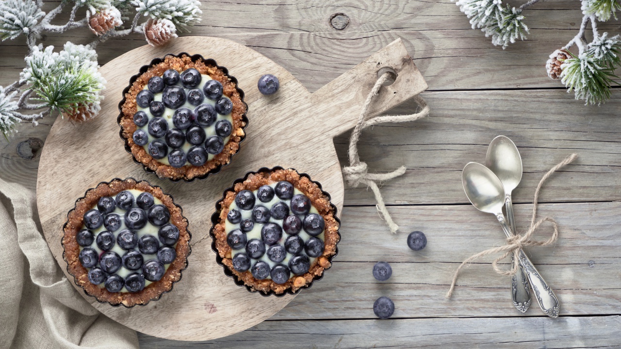 Кексы с кремом и ягодами черники на столе с чайными ложками