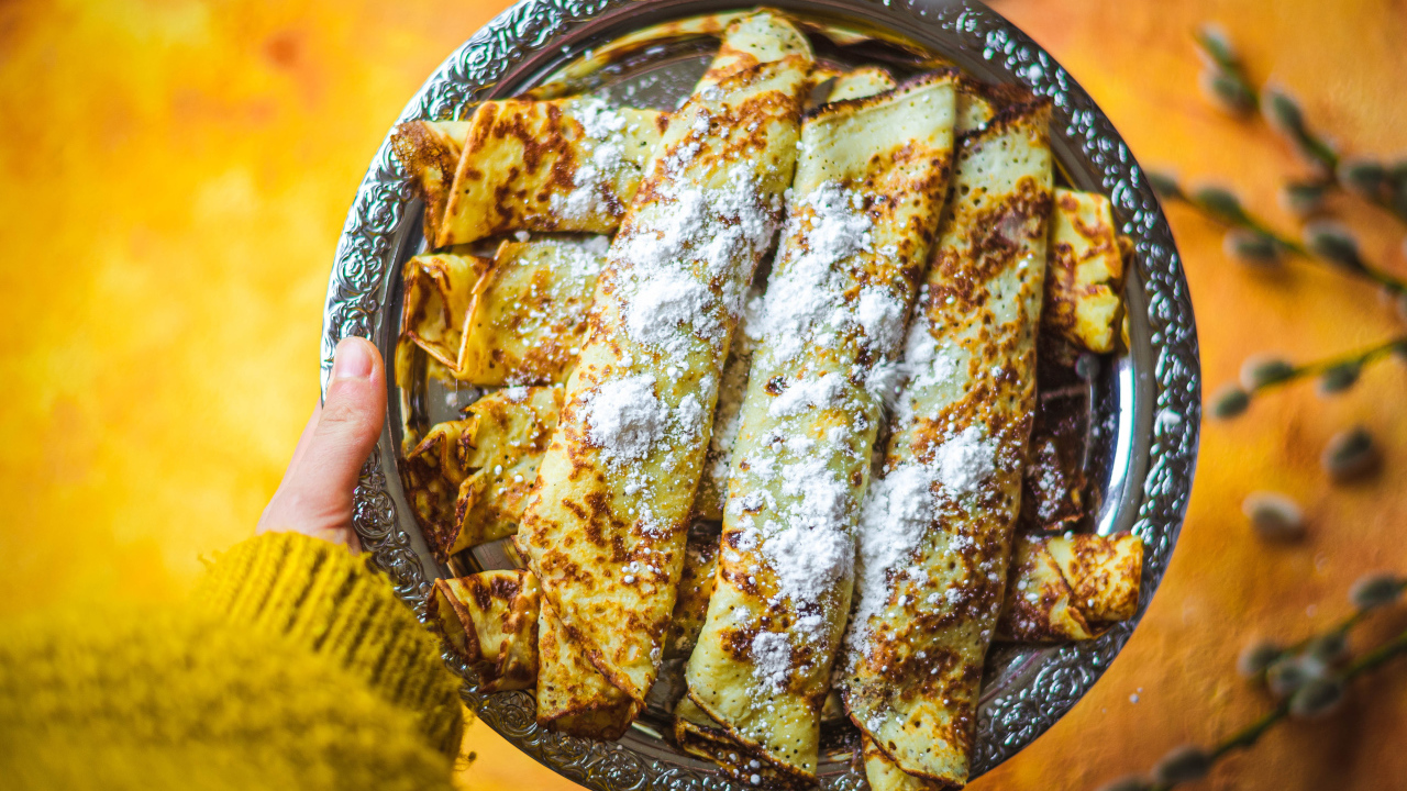 Вкусные тонкие блины с сахарной пудрой на блюде