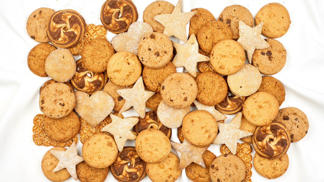 Много песочного печенья разной формы на белом фоне