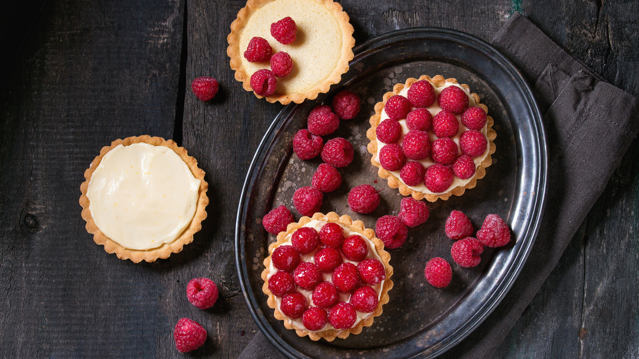 Кексы с кремом на блюде с малиной 