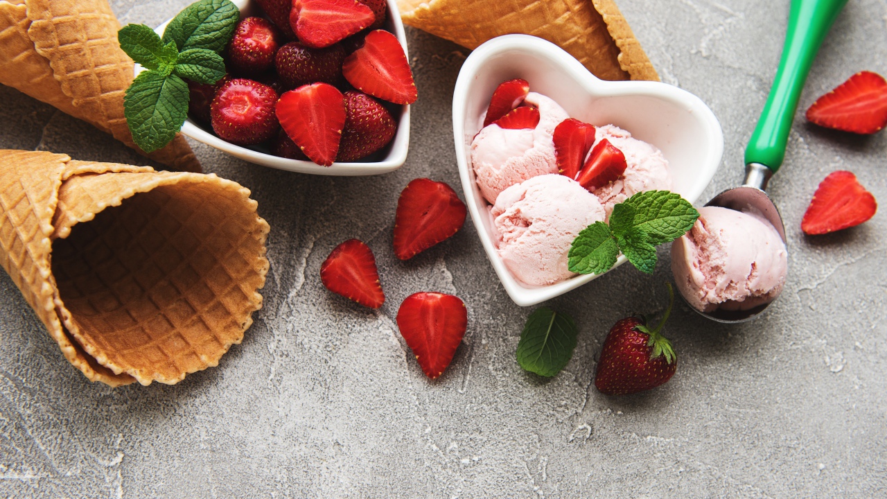 Вафельные рожки на столе с фруктовым мороженым и ягодами клубники 