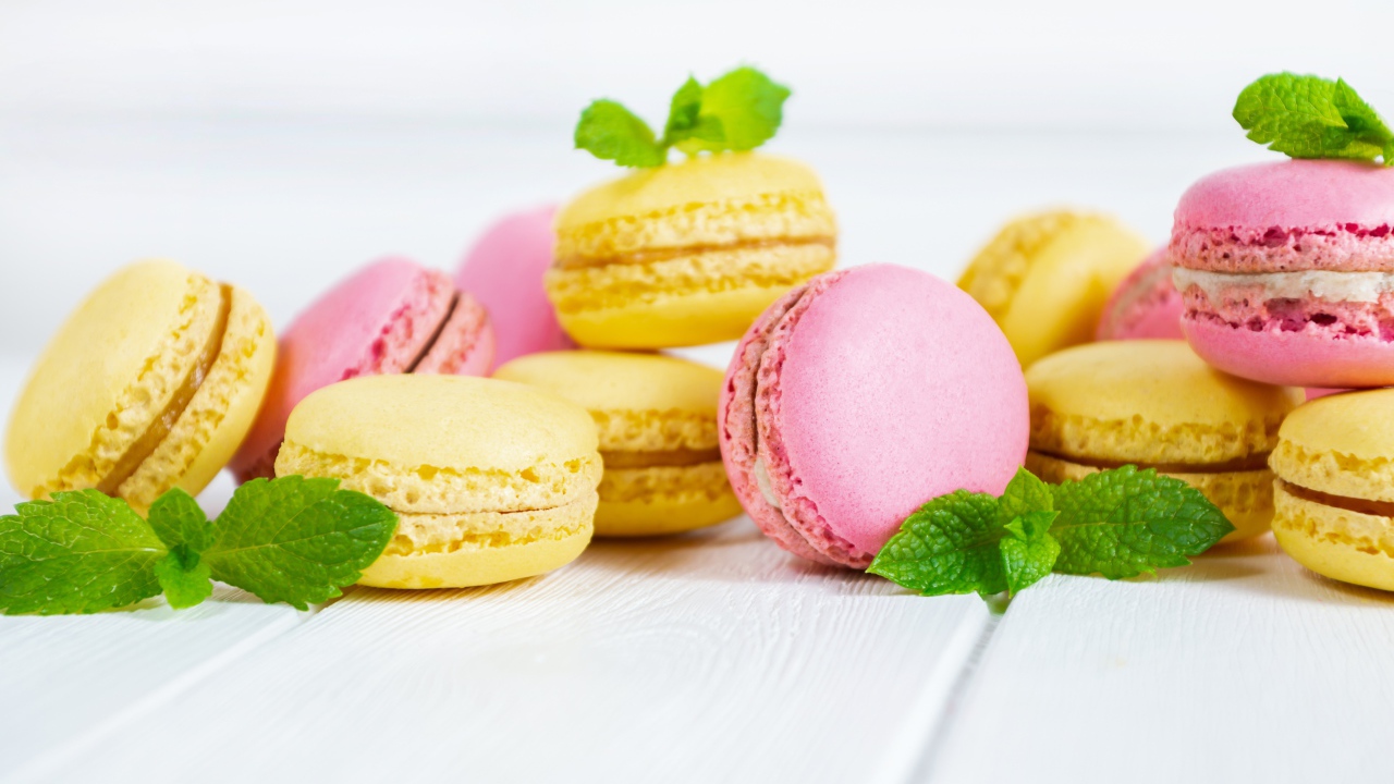 Желтый и розовый десерт макарун на белом фоне с мятой