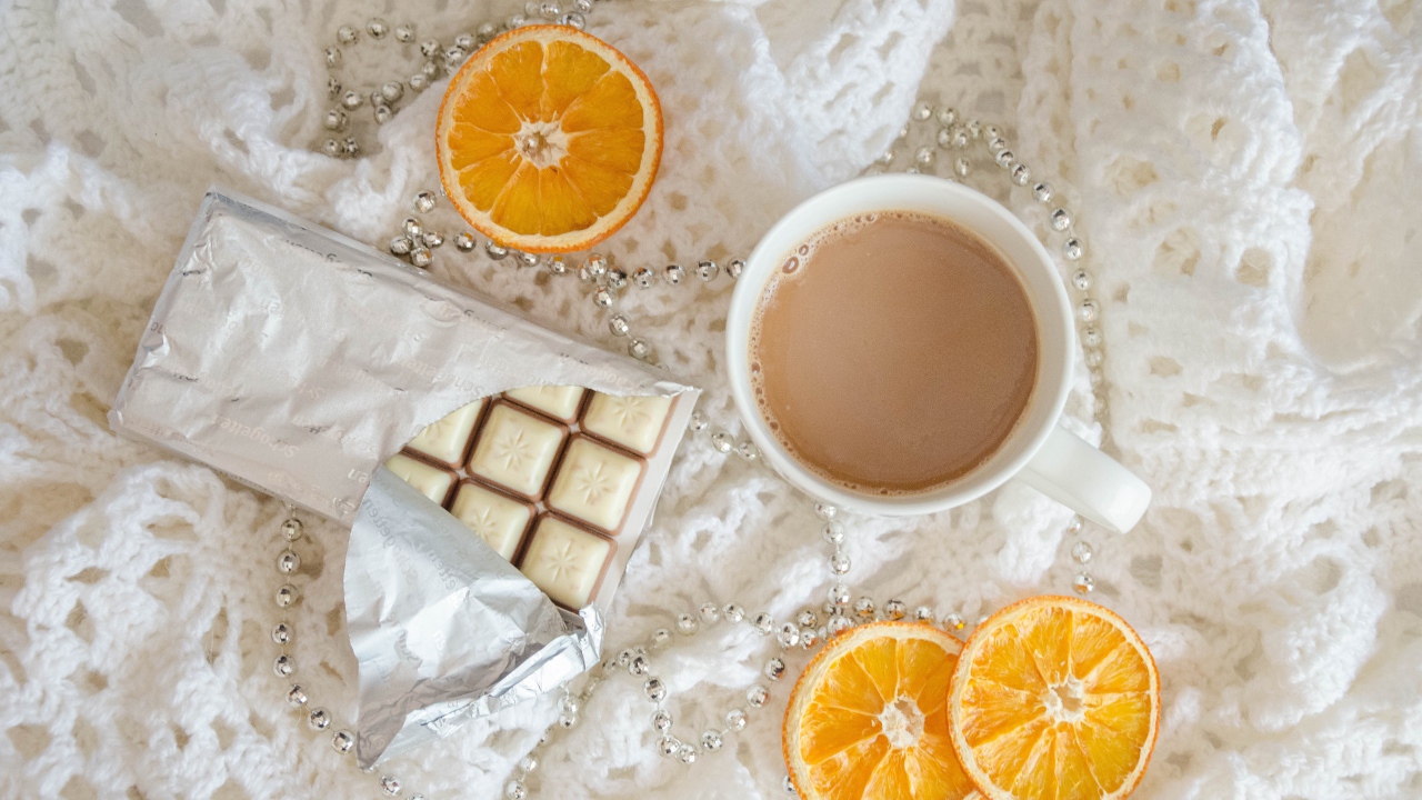 Чашка какао, шоколад и апельсин на белом пледе