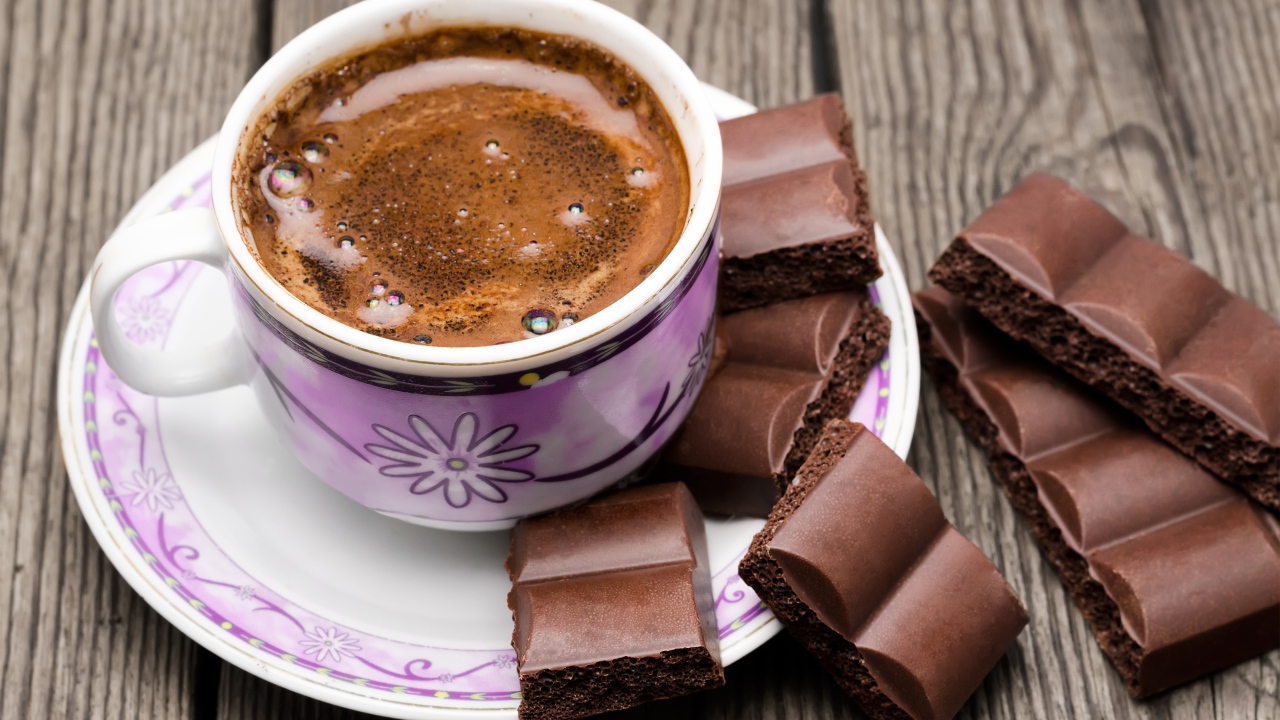 Чашка кофе на столе с кусочками шоколада