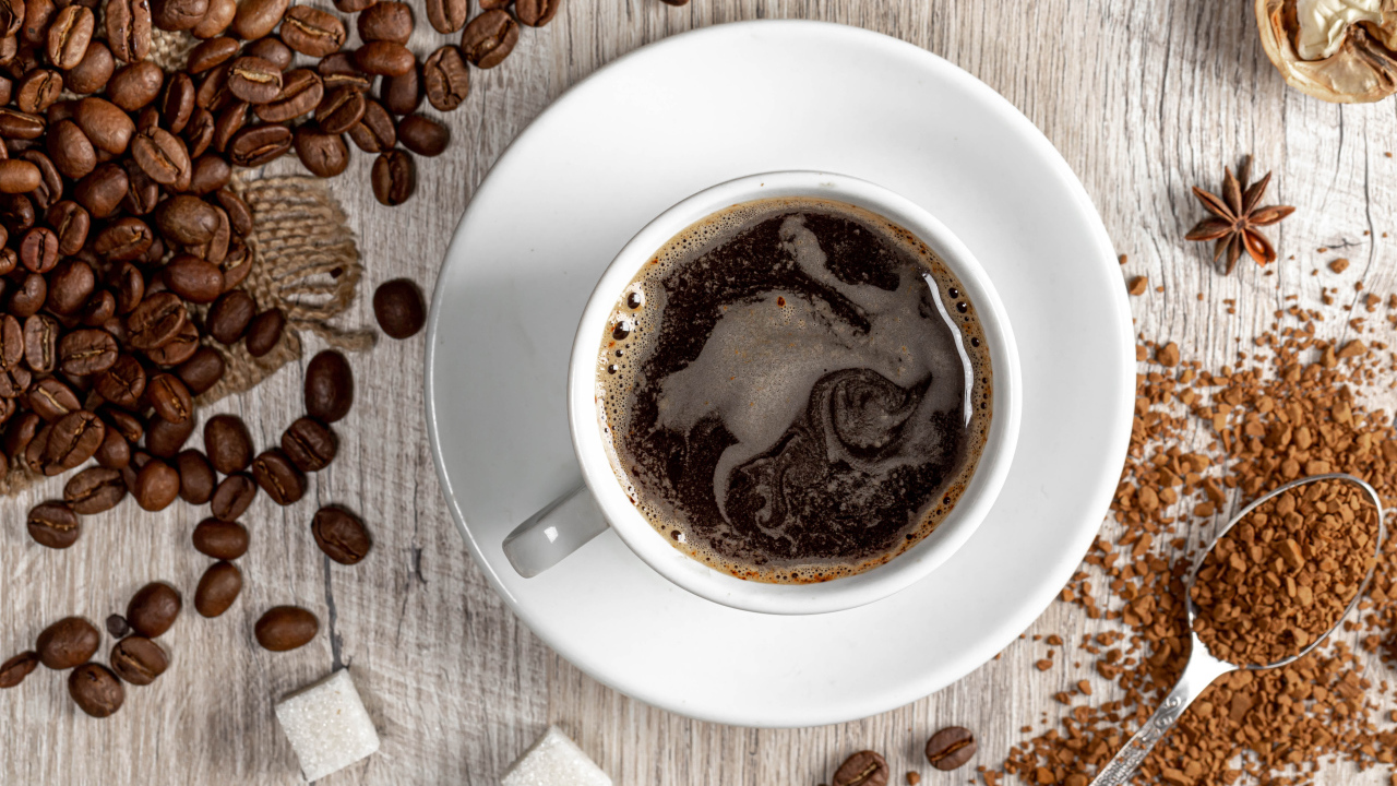 Чашка кофе на столе с сахаром и кофейными зернами