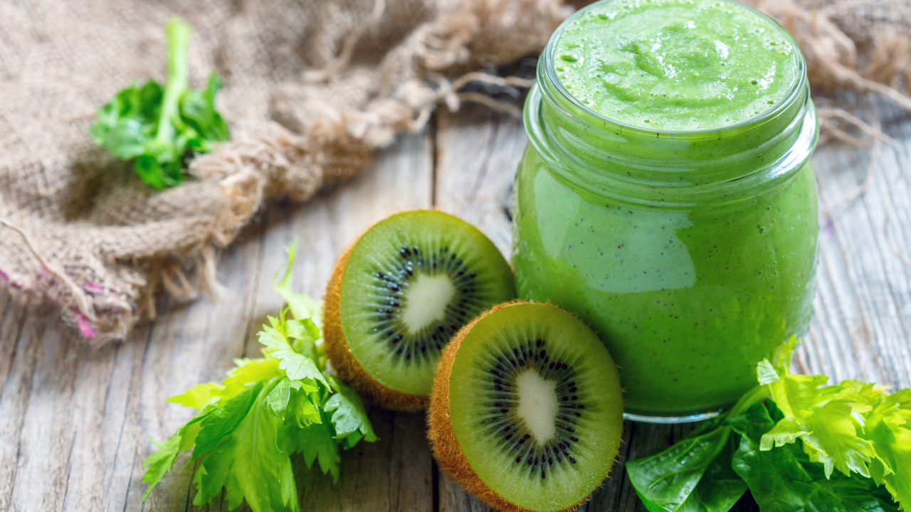 Зеленое смузи на столе с киви и зеленью 