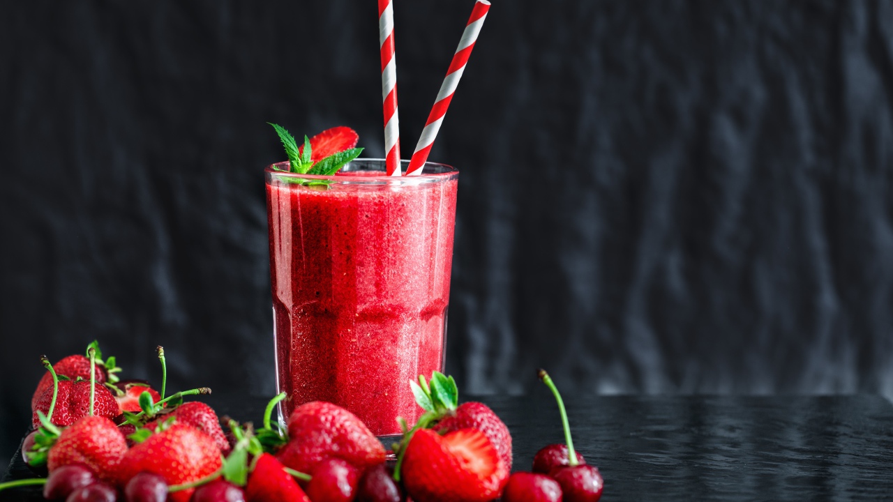Смузи с ягодами клубники и вишни на столе