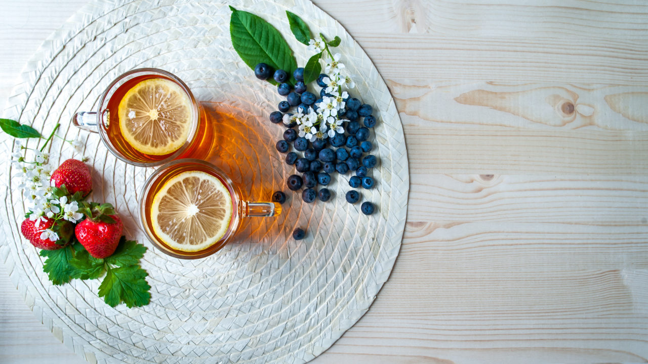 Чай с лимоном на столе с ягодами клубники и черники