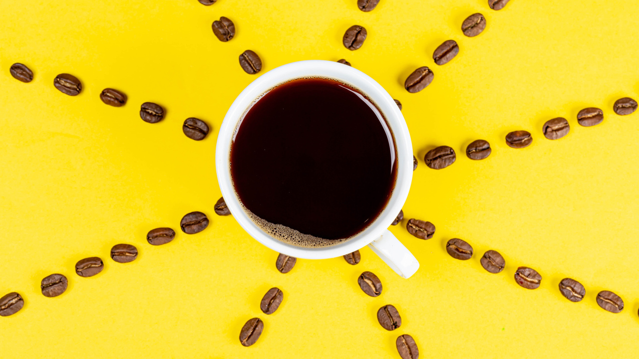 Солнце из чашки кофе с зернами на желтом фоне