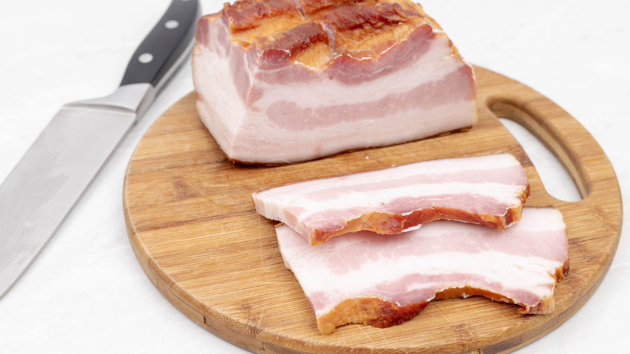 Кусок вкусного копченого сала на доске с ножом