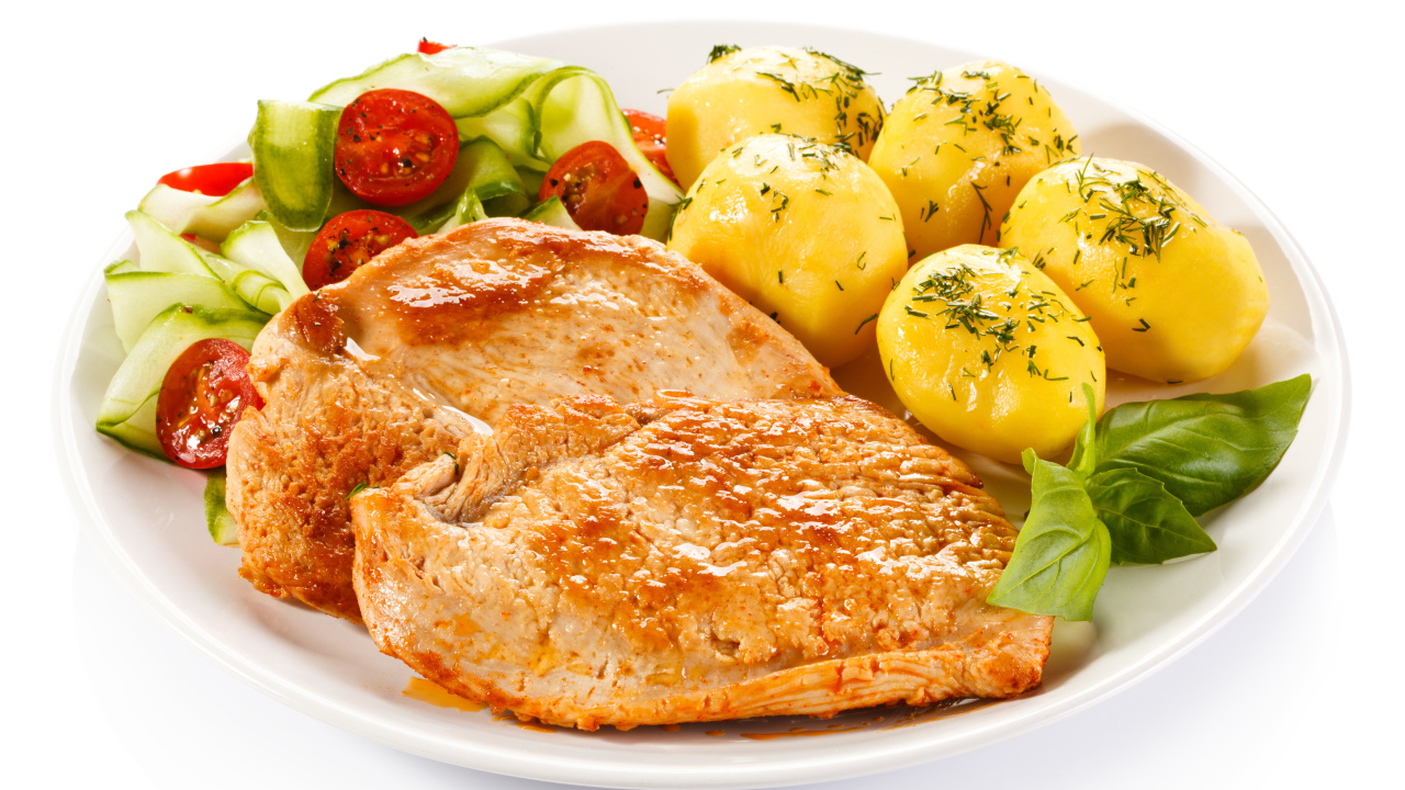 Кусок сочного куриного мяса на тарелке с картофелем и салатом