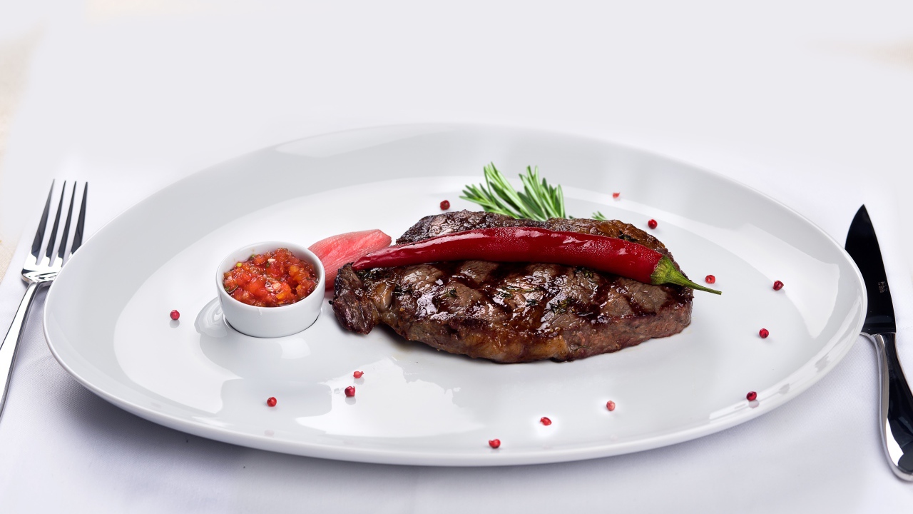 Стейк с кровью на тарелке с красным перцем