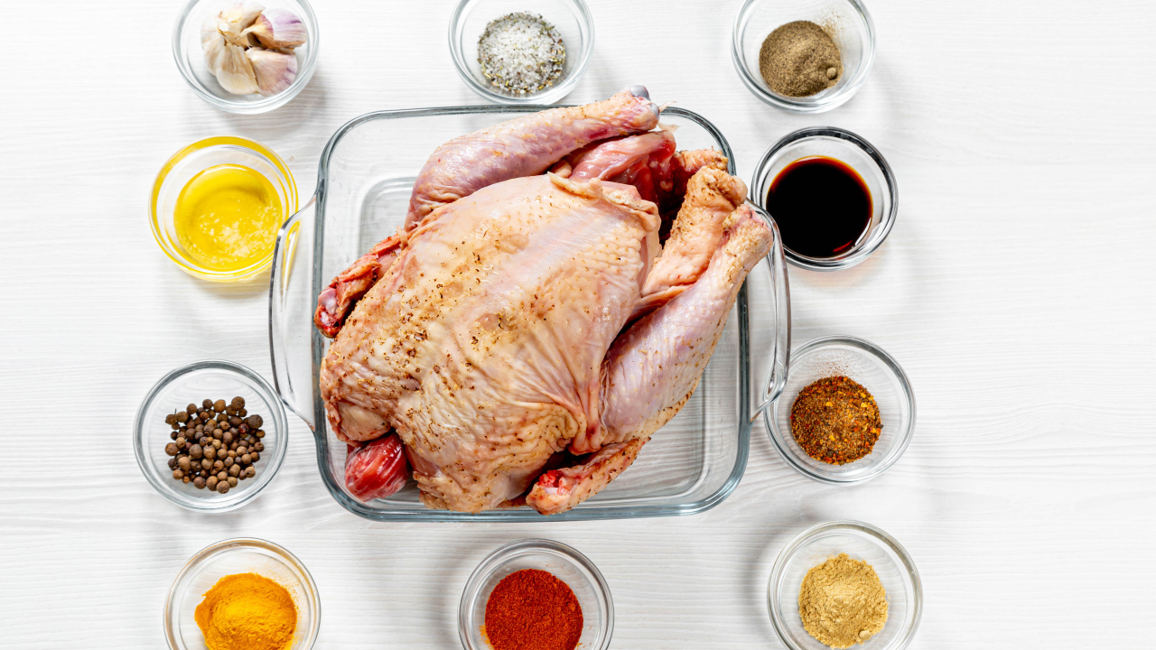 Свежая курица на противне на столе со специями 