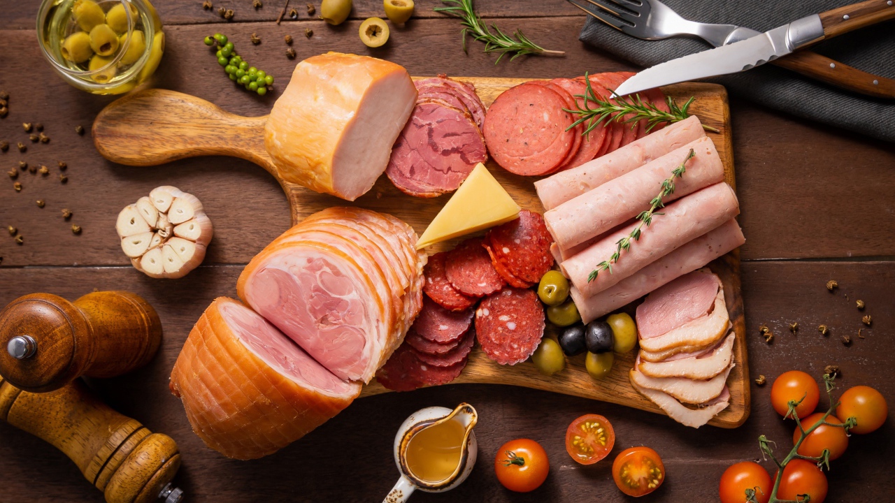 Колбасы и мясные продукты на доске со специями