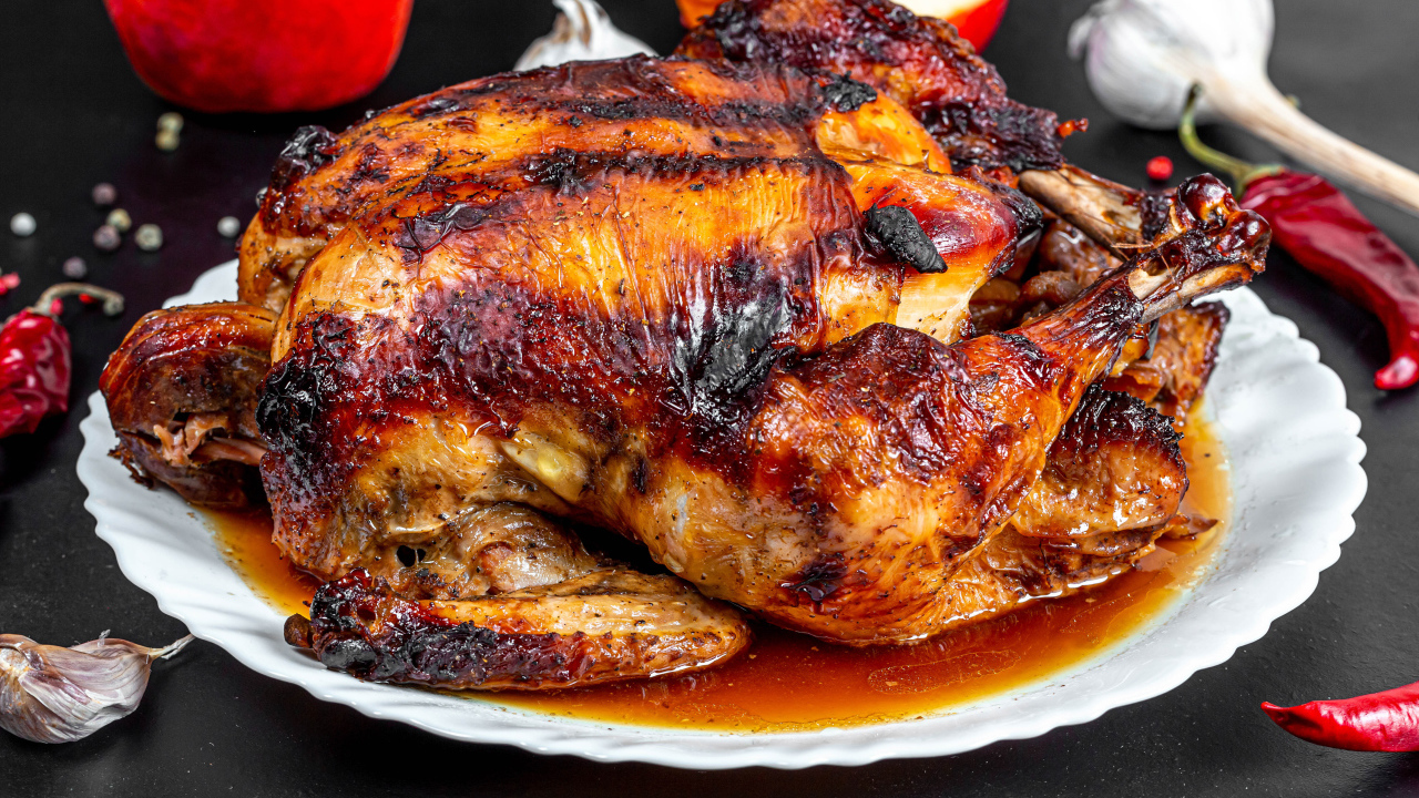 Вкусная запеченная курица на белой тарелке на столе с овощами