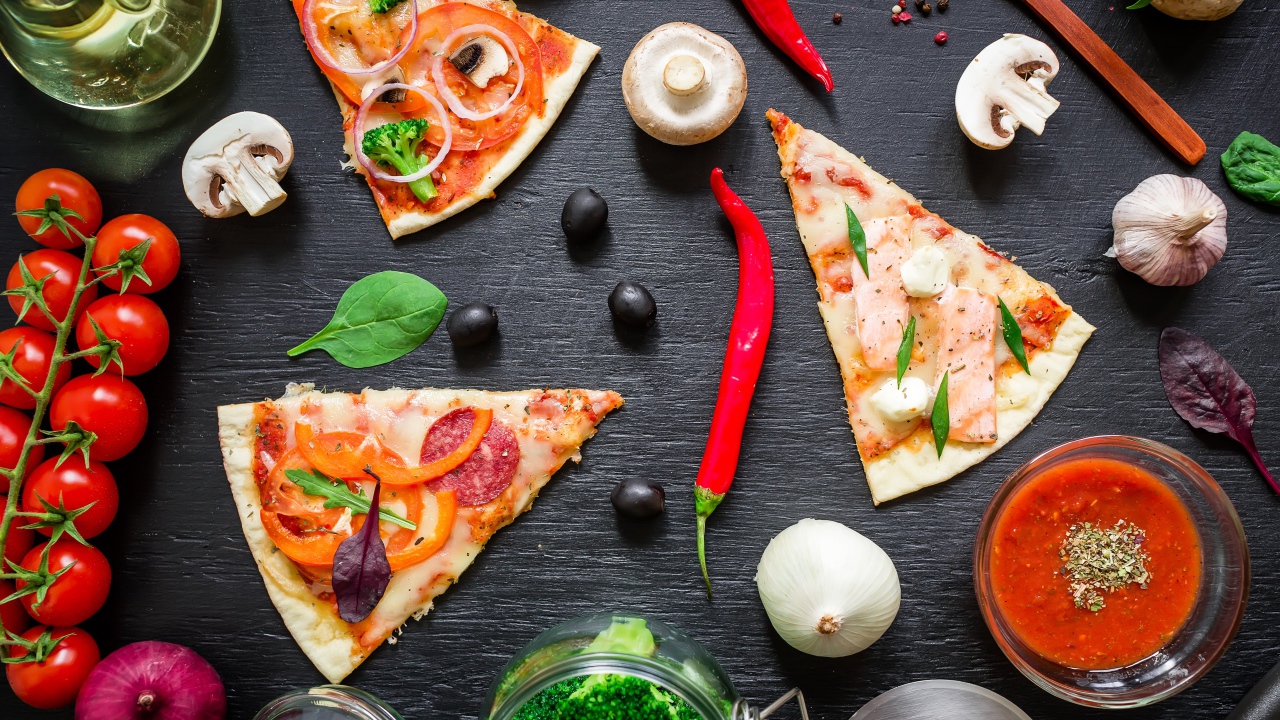 Куски пиццы на столе с овощами и соусом