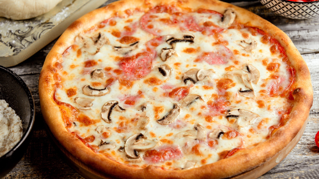 Вкусная пицца с грибами, колбасой и сыром