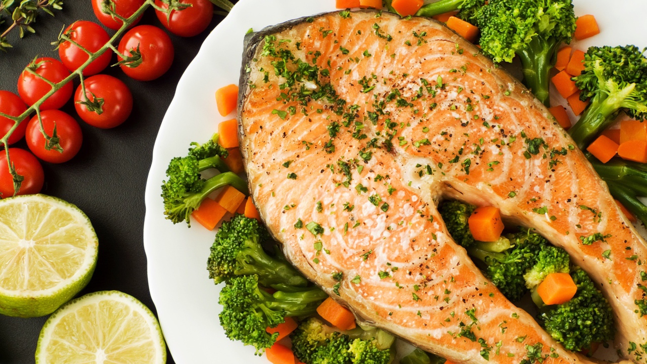 Кусок красной рыбы на тарелке с морковью и брокколи 