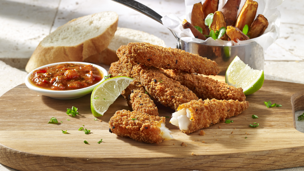 Рыба в панировке на столе с соусом и кусочками лайма