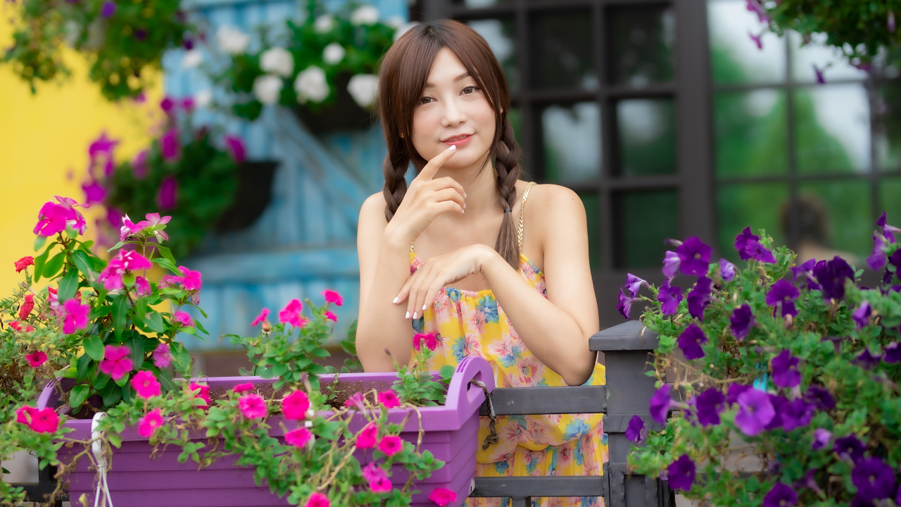 Милая азиатка стоит у кашпо с цветами петунии 