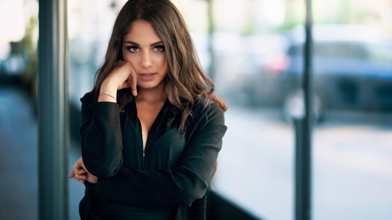 Милая девушка в черном наряде стоит на остановке