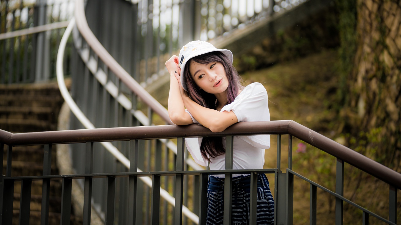 Молодая девушка азиатка стоит на лестнице у перил 