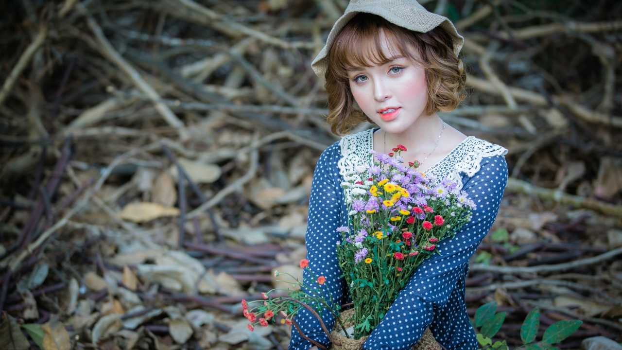 Молодая девушка азиатка с букетом цветов сидит на ветках