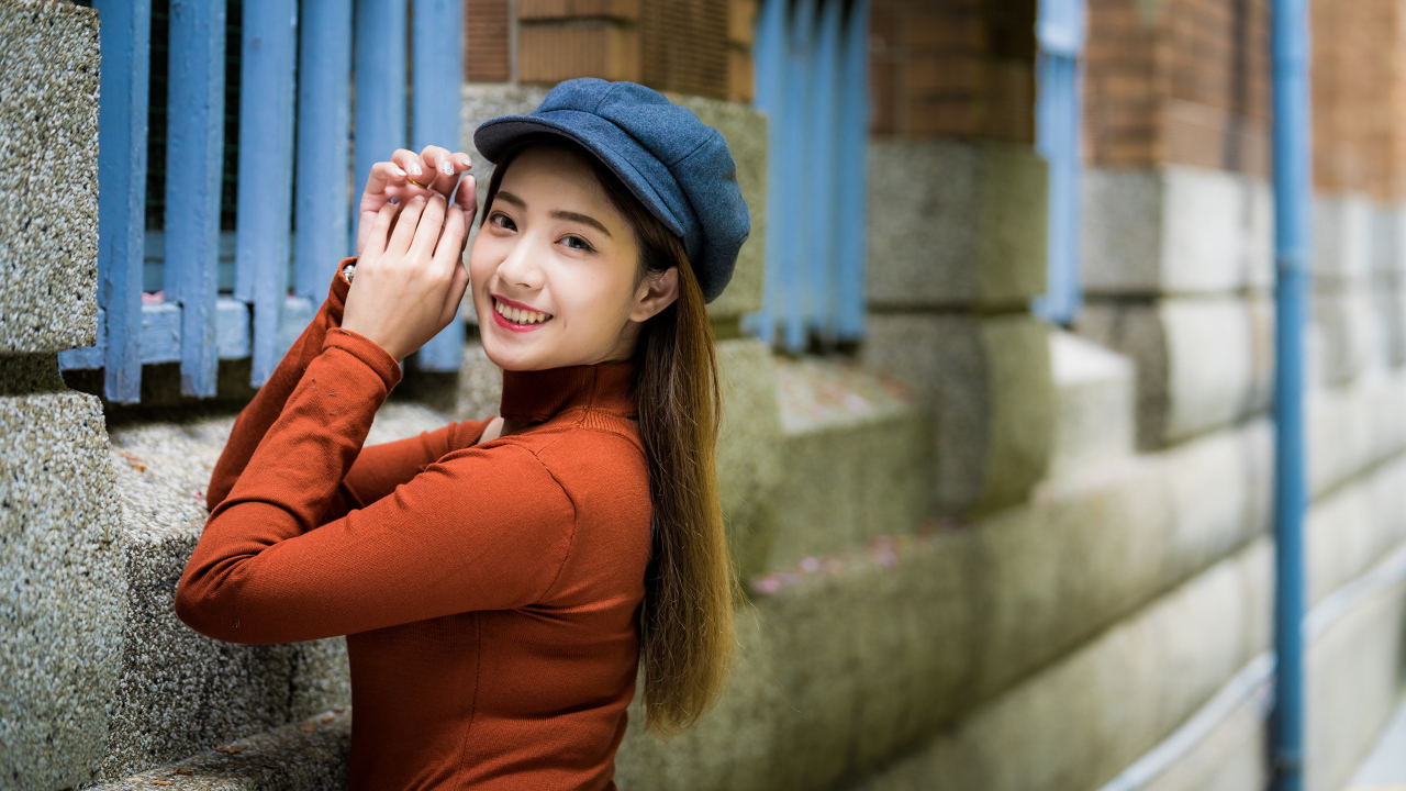 Девушка азиатка в кепке на стенке 