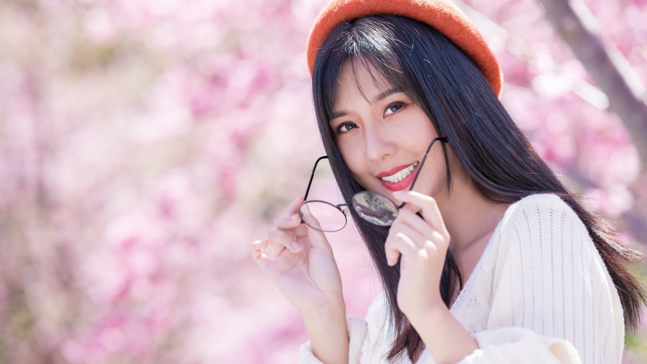 Девушка азиатка в красном берете с очками в руках