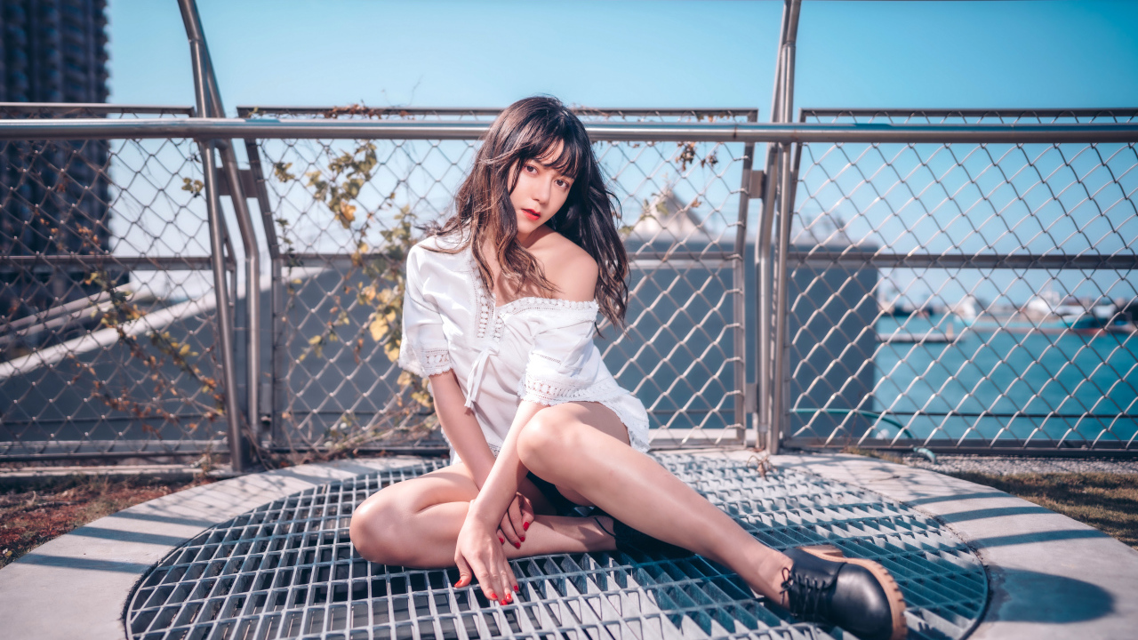 Девушка азиатка в белом наряде сидит на сетке