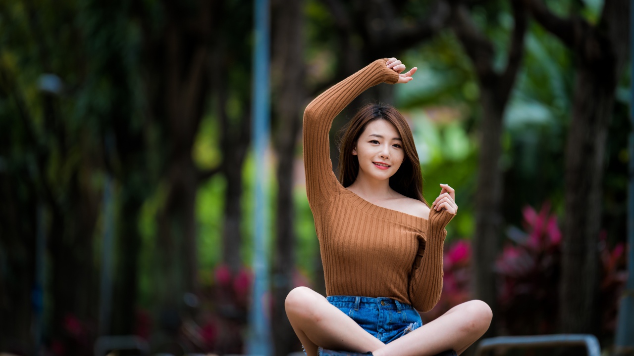 Девушка азиатка сидит в позе лотоса в парке 