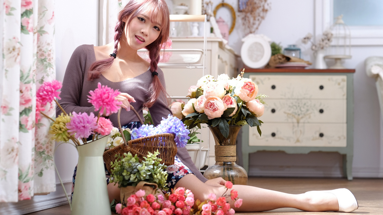 Девушка азиатка сидит с цветами на полу у окна