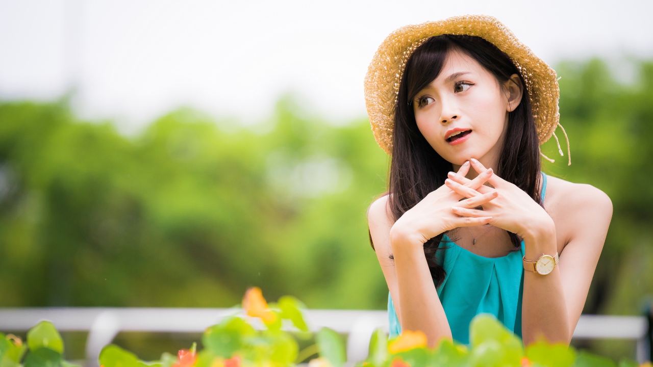 Девушка азиатка с часами на руке в шляпе