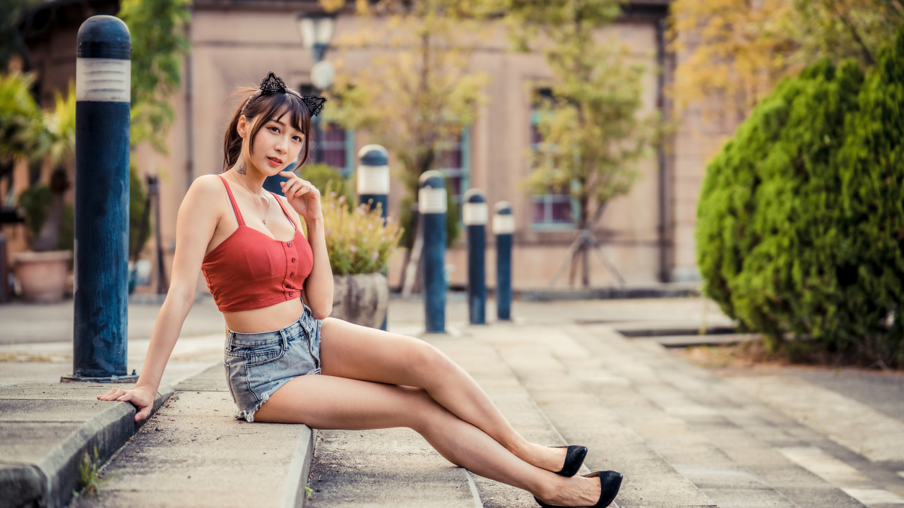 Азиатка в шортах сидит на ступенях 