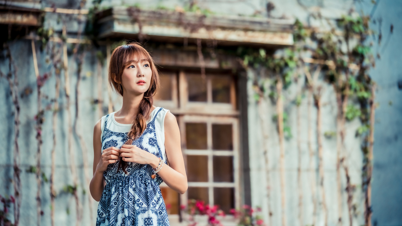Красивая девушка азиатка в сарафане у старого дома 