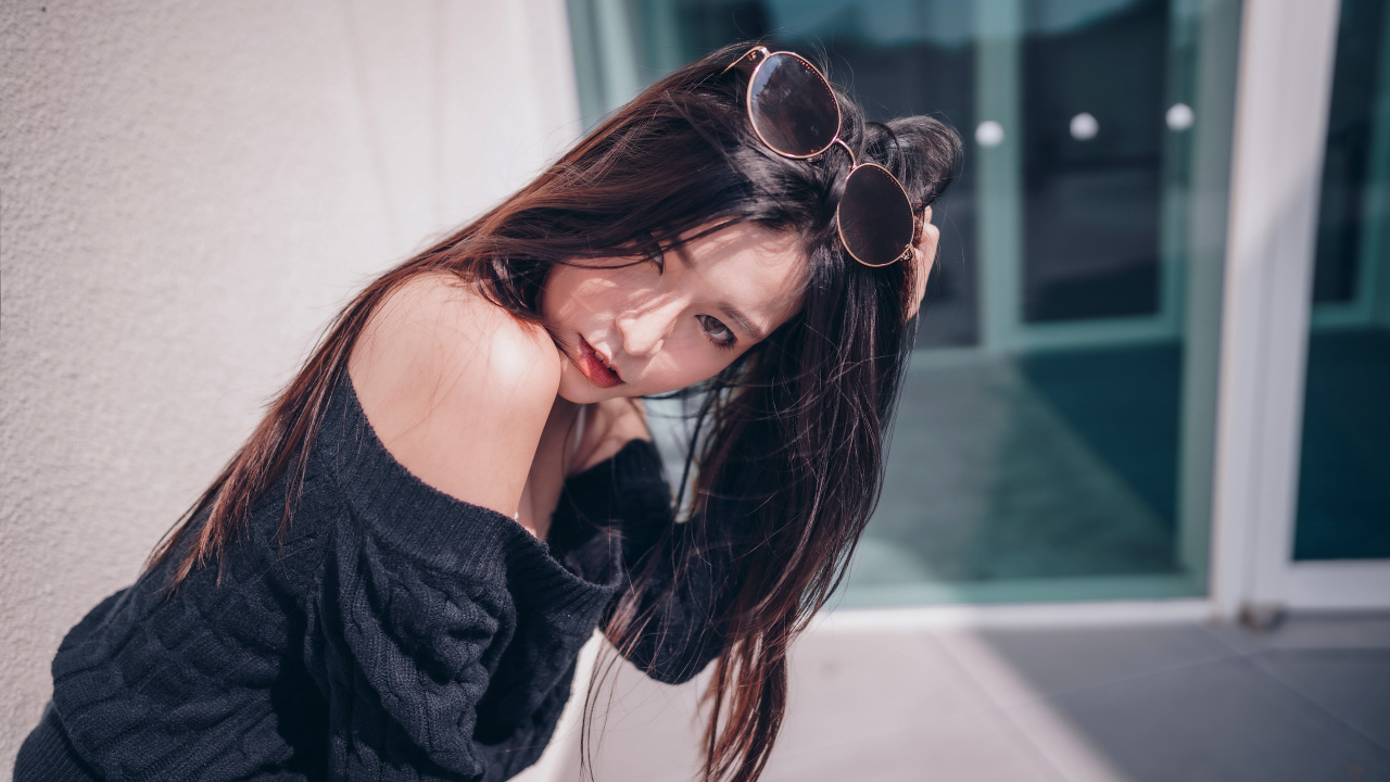 Красивая азиатка в черном свитере с солнечными очками на голове 