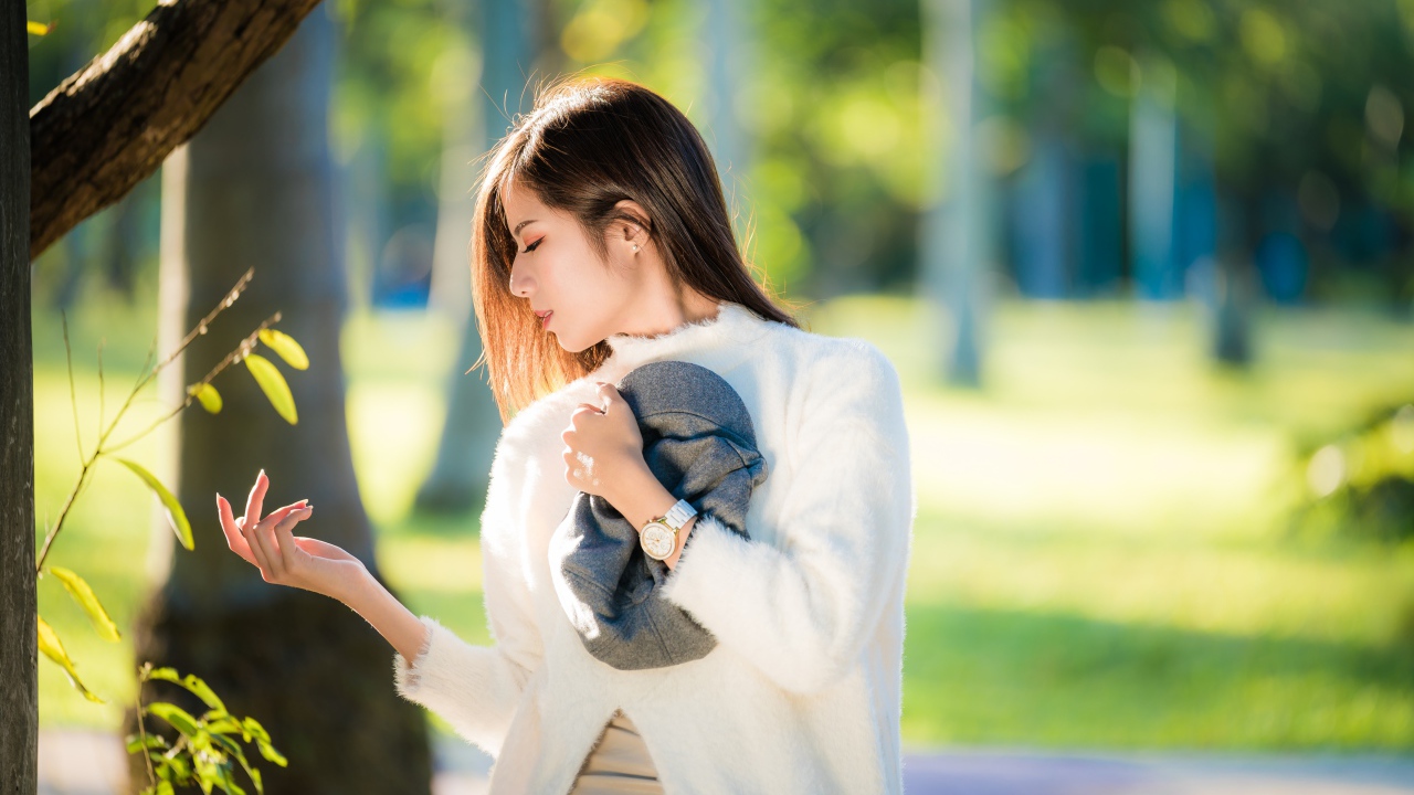 Красивая азиатка в белой кофте в солнечном парке
