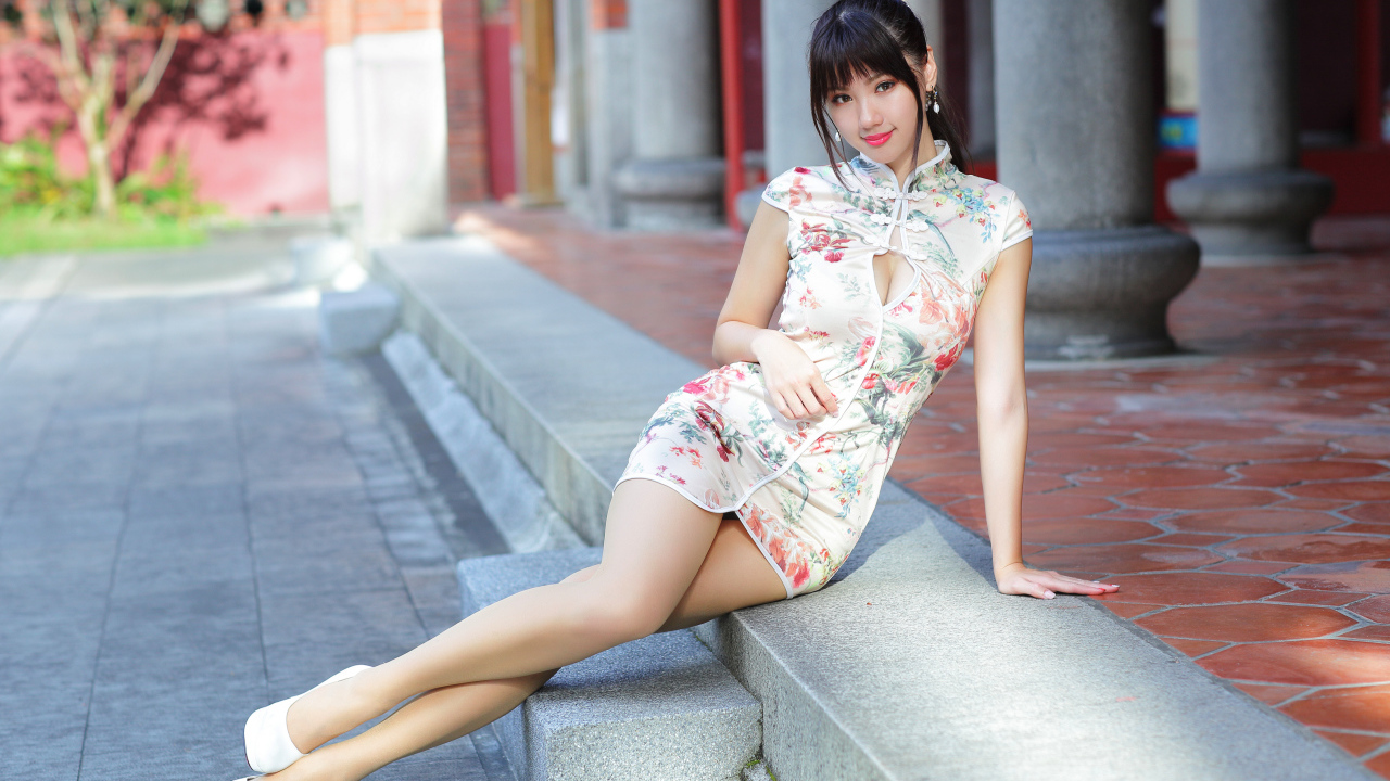 Красивая девушка азиатка в платье сидит на ступеньках