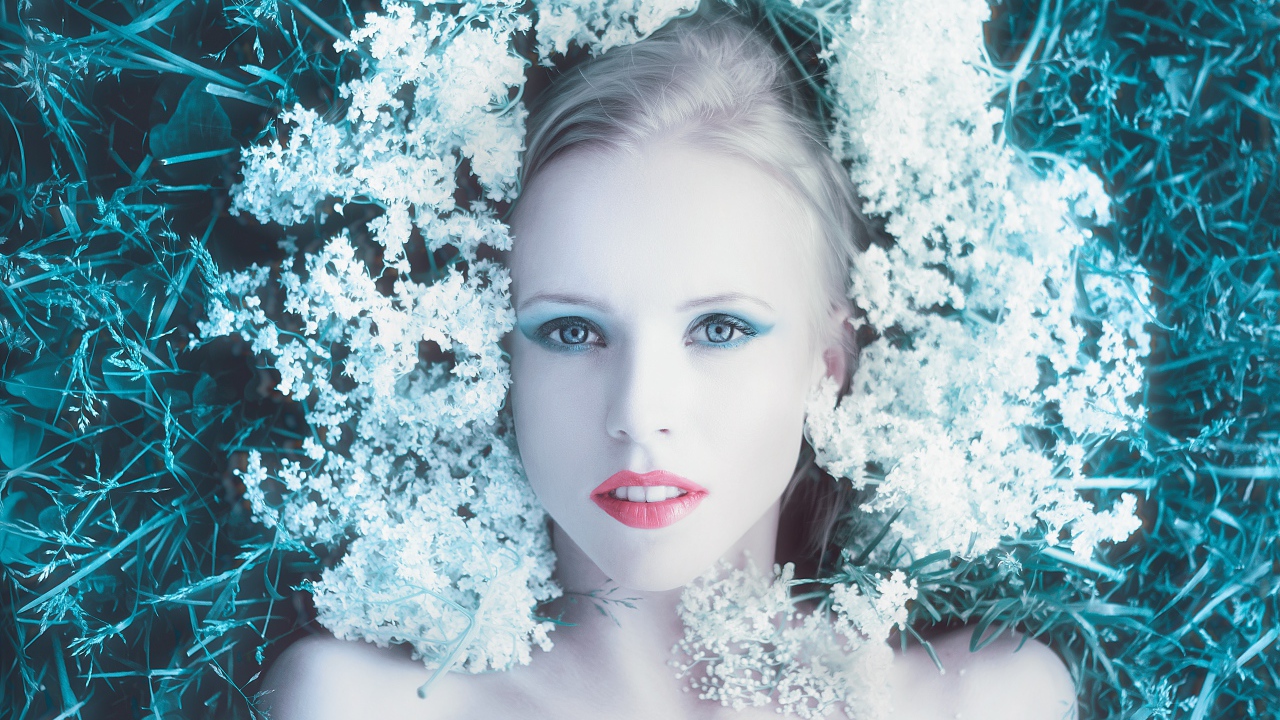 Красивая голубоглазая девушка на траве с белыми цветами